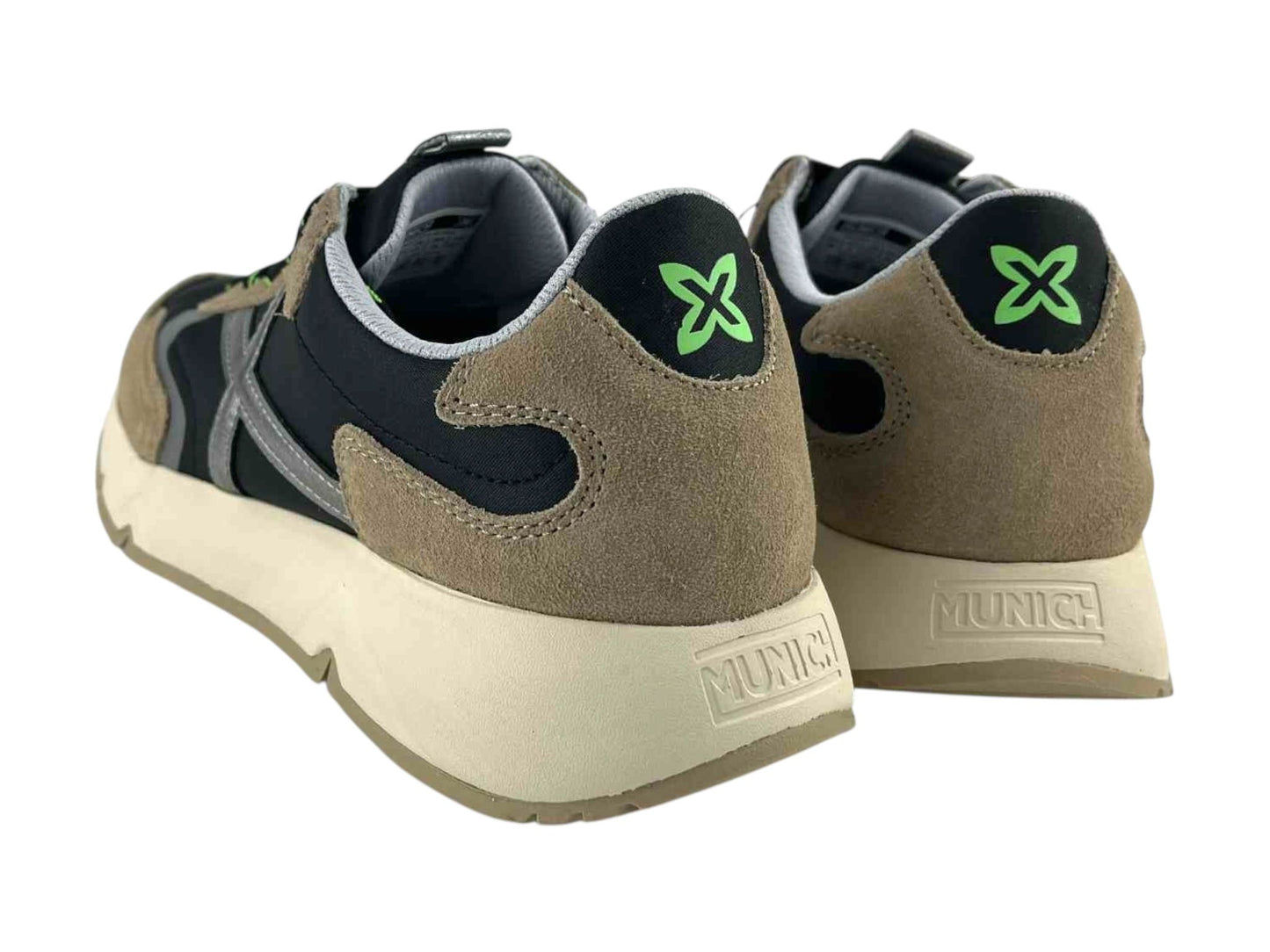 Vista por la parte de atrás de unas zapatillas negras, con detalles en beige. En el talón, logo de la marca en verde sobre fondo negro y logo de la marca en la goma de la marca Munich.
