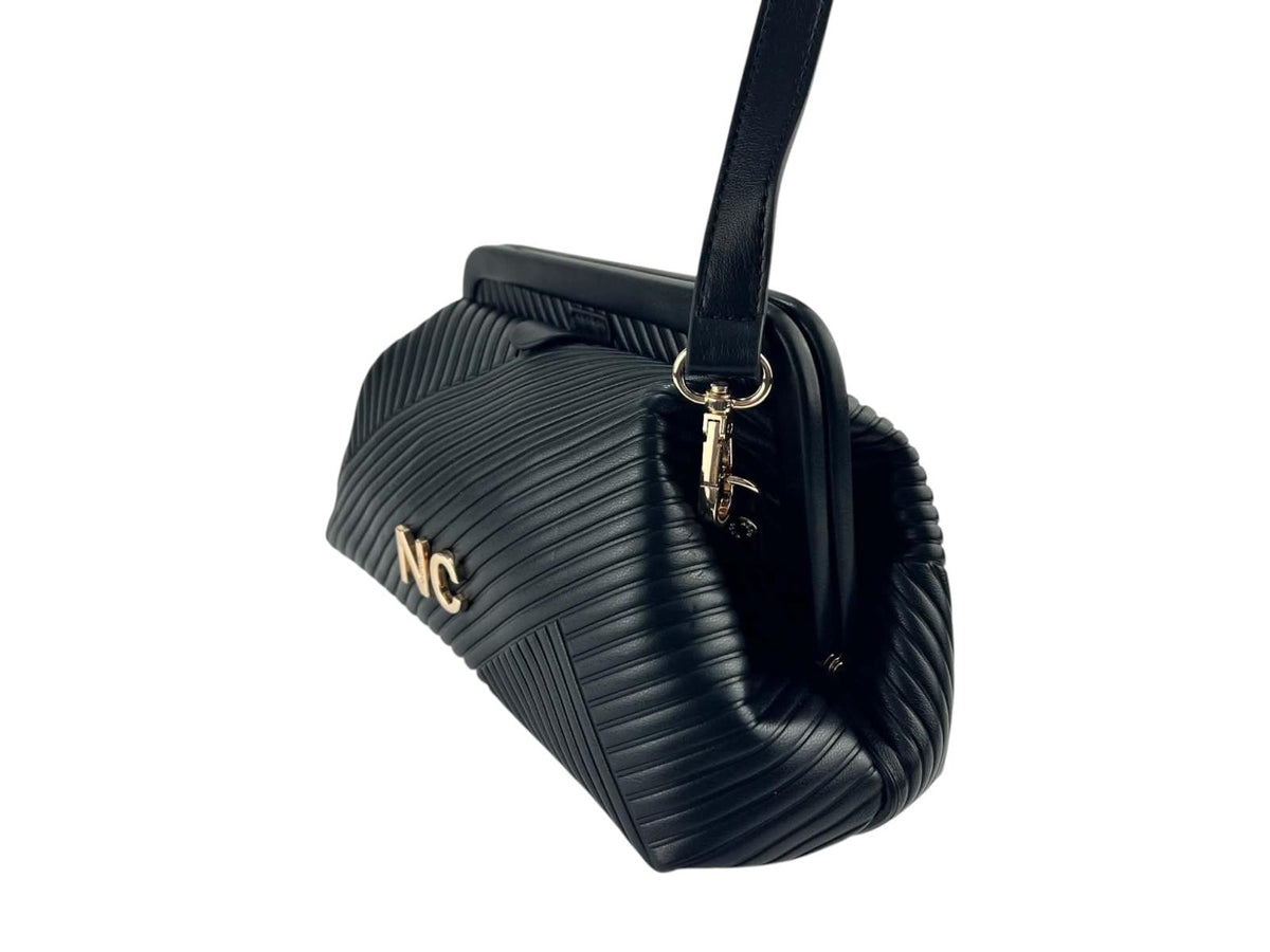 Vista lateral del bolso de mano Nocco negro plisado, con volumen compacto, herrajes dorados y detalle NC.