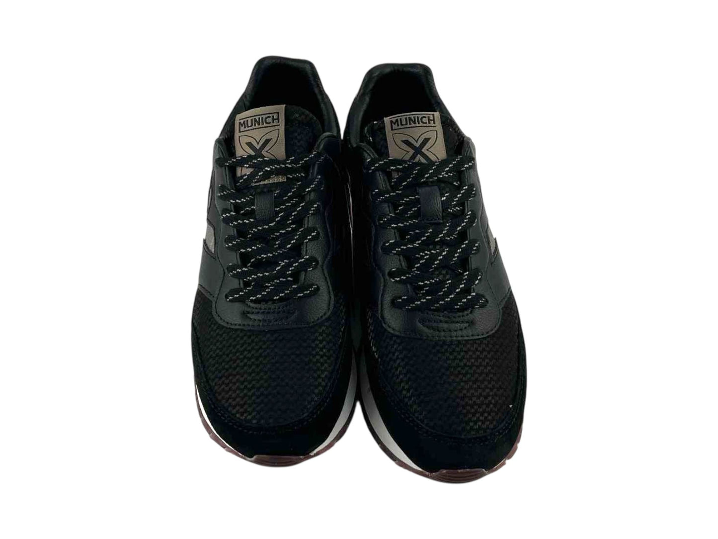 Vista frontal de unas zapatillas de mujer, de la marca Munich, con detalles de piel y textil, en diferentes texturas, logo de la marca en la lengüeta en tono metalizado y cordones negros.