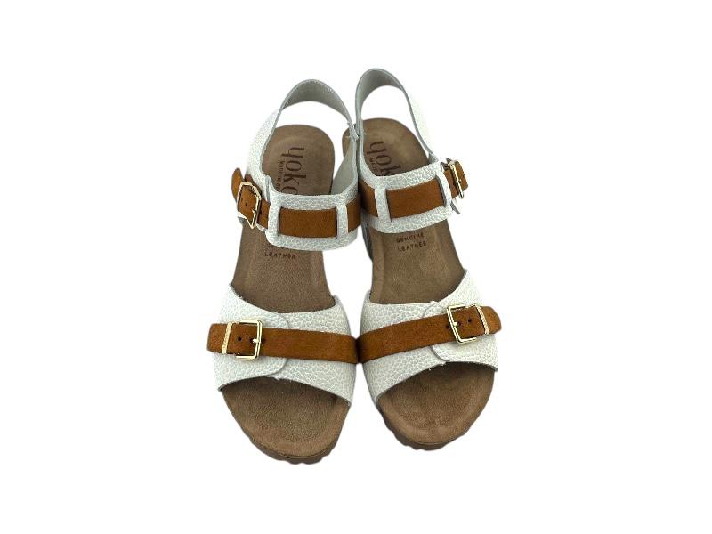 Vista frontal de unas sandalias ergonómicas de estilo casual, regulables en empeine y tobillo por hebillas plateadas, en tiras de color avellana. Fondo blanco.