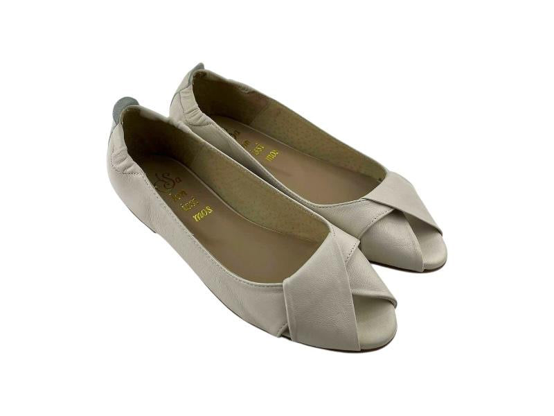 Vista lateral  izquierda de unos zapatos planos en piel peep toe con nudo en el empeine sobre fondo blanco.