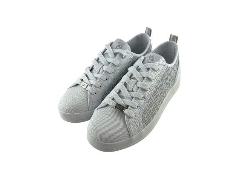 Vista lateral derecha de unos tenis urbanos elegantes, blancos, de mujer, con monograma y cierre de cordones, sobre fondo blanco. 