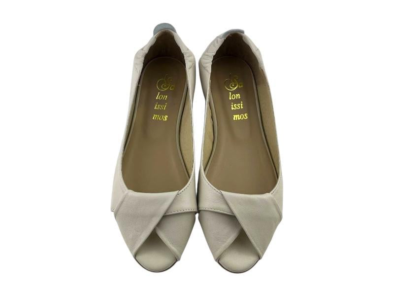 Vista frontal de unos zapatos en piel beige, peep toe,  con nudo en el empeine sobre fondo blanco.