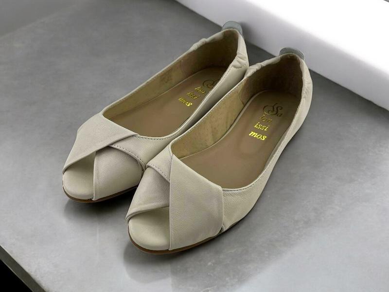 Vista lateral de unos zapatos en piel peep toe con nudo en el empeine sobre fondo blanco.