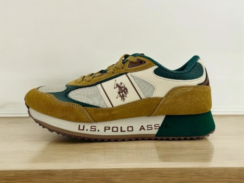 Sneakers de hombre en piel con cordones en ocre y verde, logo de la marca en el lateral. Vista lateral izquierda sobre fondo de madera clara.