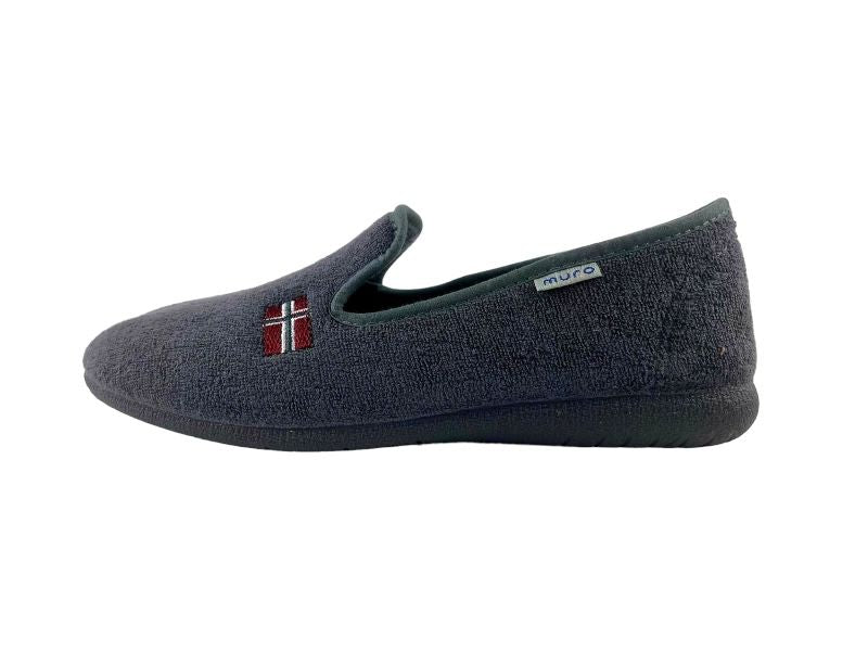 Vista lateral de una zapatilla de casa de verano unisex en color gris con bandera bordada y suela de goma. Vista lateral izquierda sobre alfombra blanca.