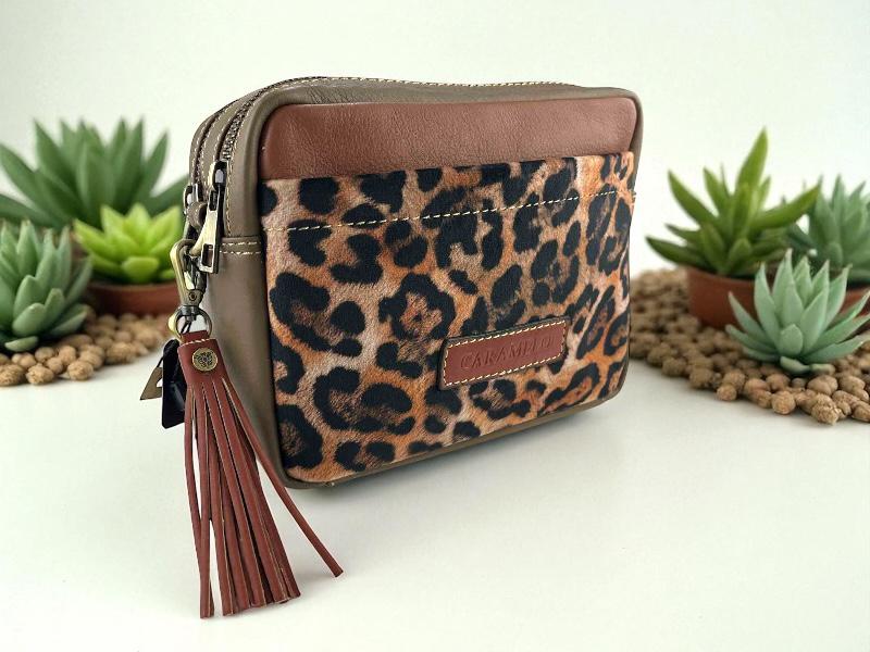 Bolso de mujer en piel legítima, de la marca Caramelo con print animal leopardo textil. Con dos departamentos separados por cremalleras y bonita borla color marrón avellana en el tirador. 