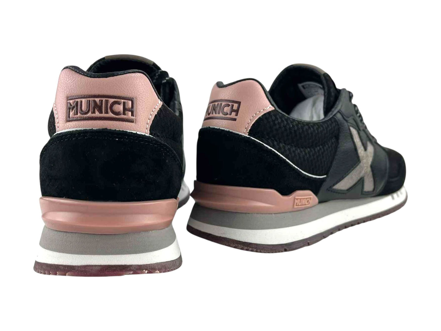 Vista por la parte de atrás de unos sneakers de calle, de mujer, de la marca Munich, con detalles en rosa y logo de la marca en el talón en color negro.