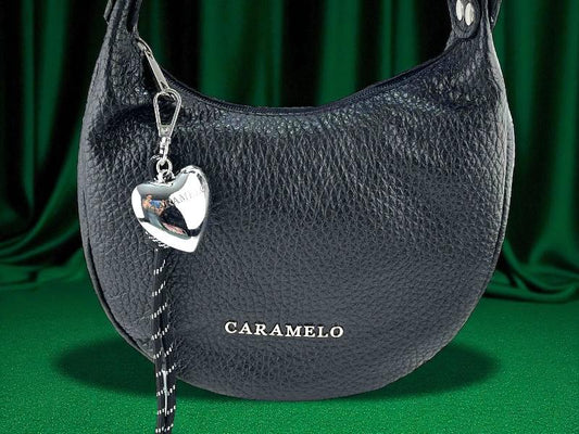 Bolso semicircular para mujer en piel legítima color negro, de gran capacidad y calidad, logo de la marca Caramelo en el frontal, accesorio extraible de Corazón.