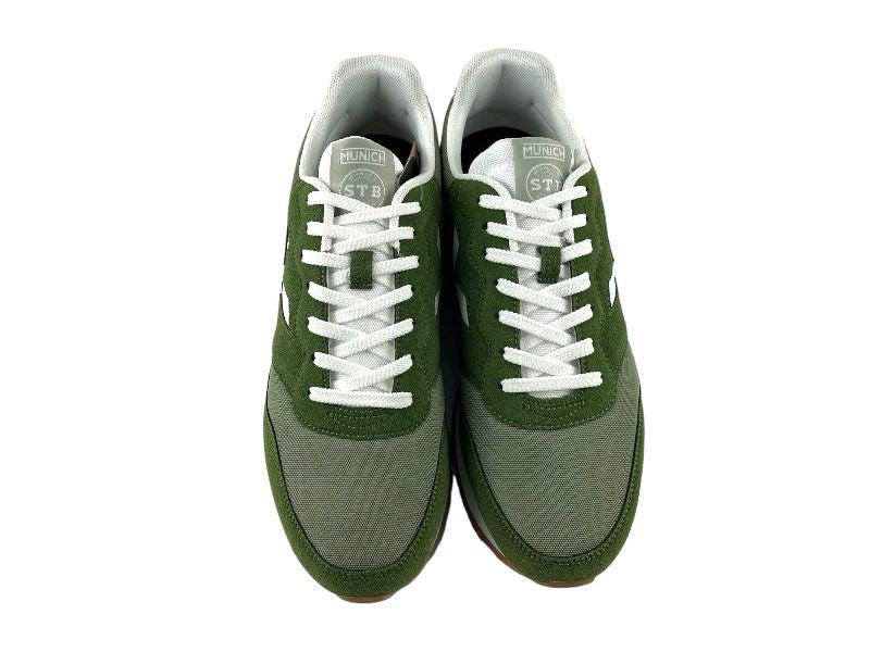 Sneakers deportivos de hombre, con diferentes tonos de verde, logo en blanco de la marca en el lateral y en la lengüeta, con cordones. Vista frontal del sneaker sobre fondo blanco.