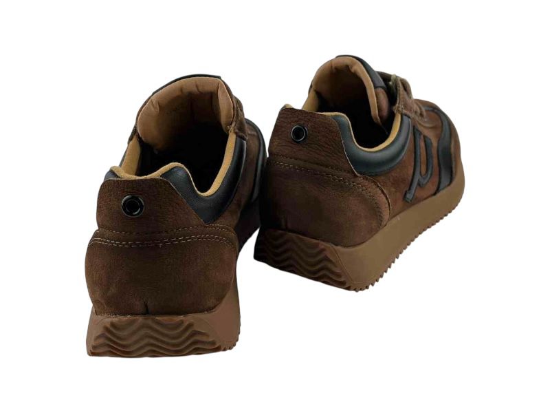 Vista por la parte de atrás de unas zapatillas de la marca española Yokono, para mujer,  estilo retro vintage, en piel marrón y negra, con suela dentada en los mismos tonos .