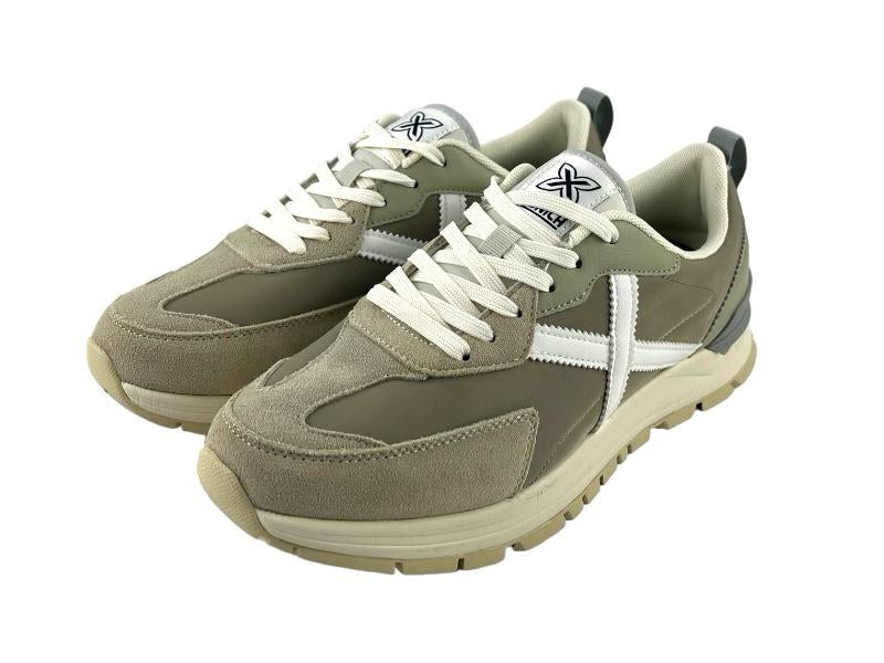 Sneakers ( tenis) de hombre, en distintos tonos de gris verdoso y logo en la lengüeta y en el lateral en color blanco, con cordones y suela en blanco. Vista lateral izquierda sobre fondo blanco.
