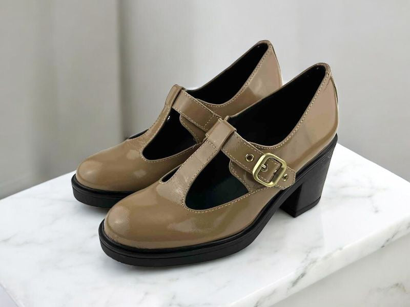 Zapatos cómodos en piel genuina charol beige, con tacón en bloque negro, estilo Mary Jane con tira en T. Cierre por hebillas en color dorado.  
