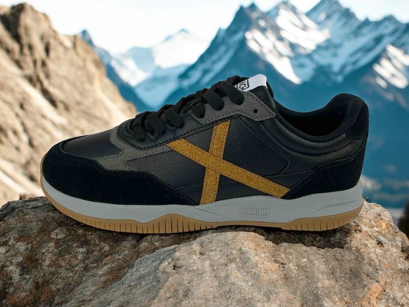 Sneakers de hombre en piel color negro, con logo de la marca en color ocre en el lateral, suela bicolor en gris y color caramelo y cordones negros.