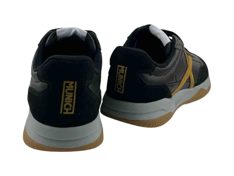 Zapatillas de hombre en color negro de estilo retro running con logo en el talón en color ocre y en el lateral en forma de X. Suela en color gris y color caramelo.