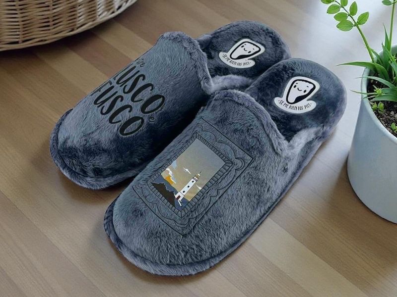 Pantuflas divertidas desclazas para hombre, dela marca española Se me ríen los pies, en paño de gran calidad color gris azulado, con diseño ergoómico muy cómodo. Eslogan Lusco Fusco y paisaje con faro.