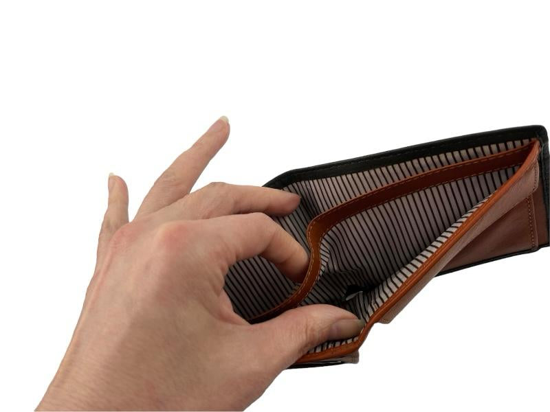Vista del interior de una billetera, con una mano separando los dos departamentos, que llevan un forro a rayas. Fondo blanco.