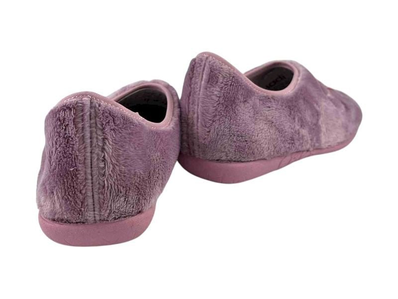 Vista por la parte de atrás de unas zapatillas rosas para mujer, en paño suave y cálido y suela de goma antideslizante.