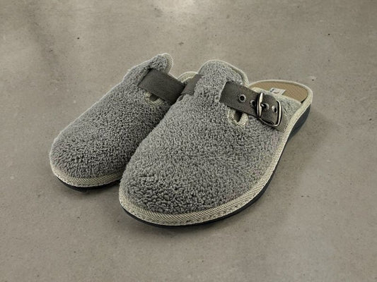 Zapatillas de casa descalzas, en algodón rizado gris perla, con hebillas regulables en el empeine. Vista lateral izquierda sobre fondo gris.
