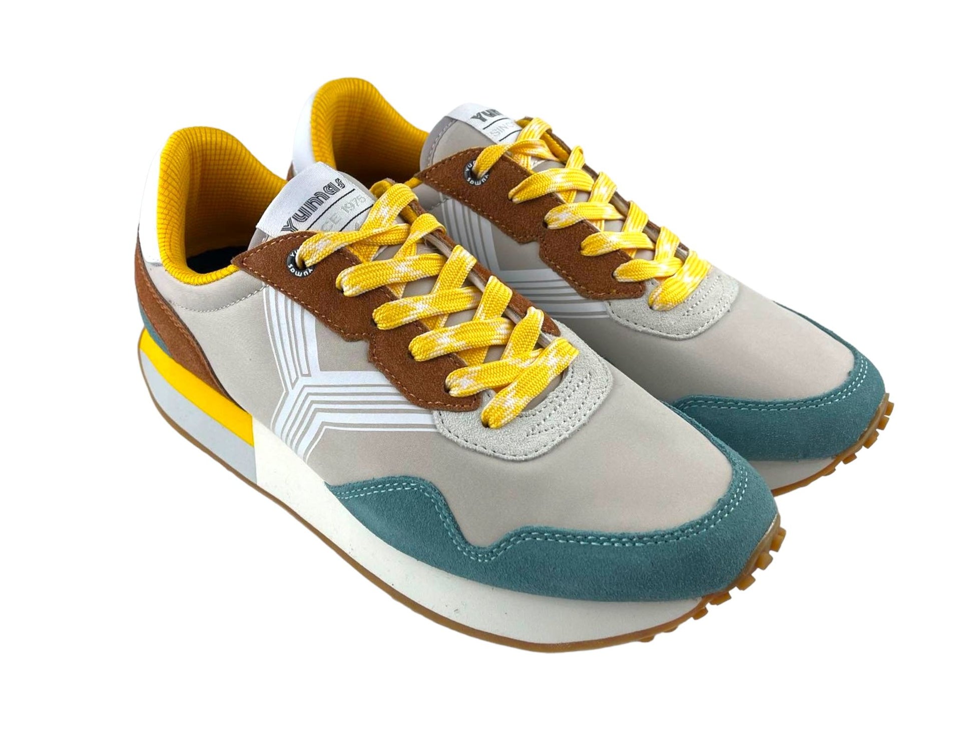 Tenis de hombre en beige con puntera en azul y cordones amarillos con detalles en blanco. Vista lateral derecha de unos tenis sobre fondo blanco.