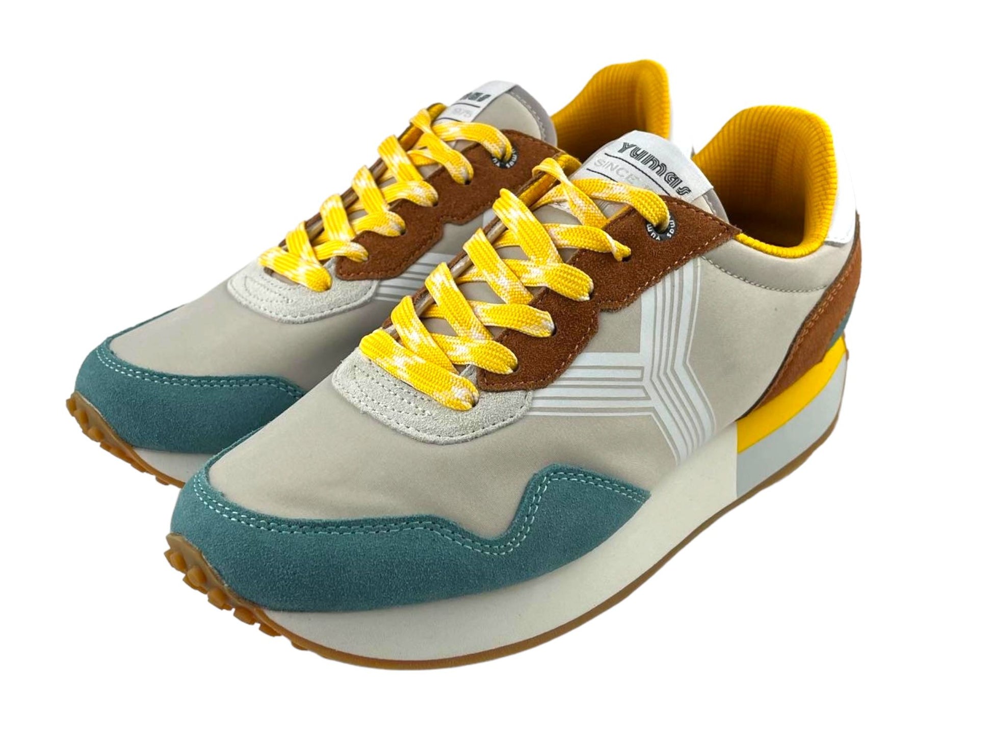 Tenis de hombre en beige con puntera en azul y cordones amarillos con detalles en blanco. Vista lateral izquierda de unos tenis sobre fondo blanco.