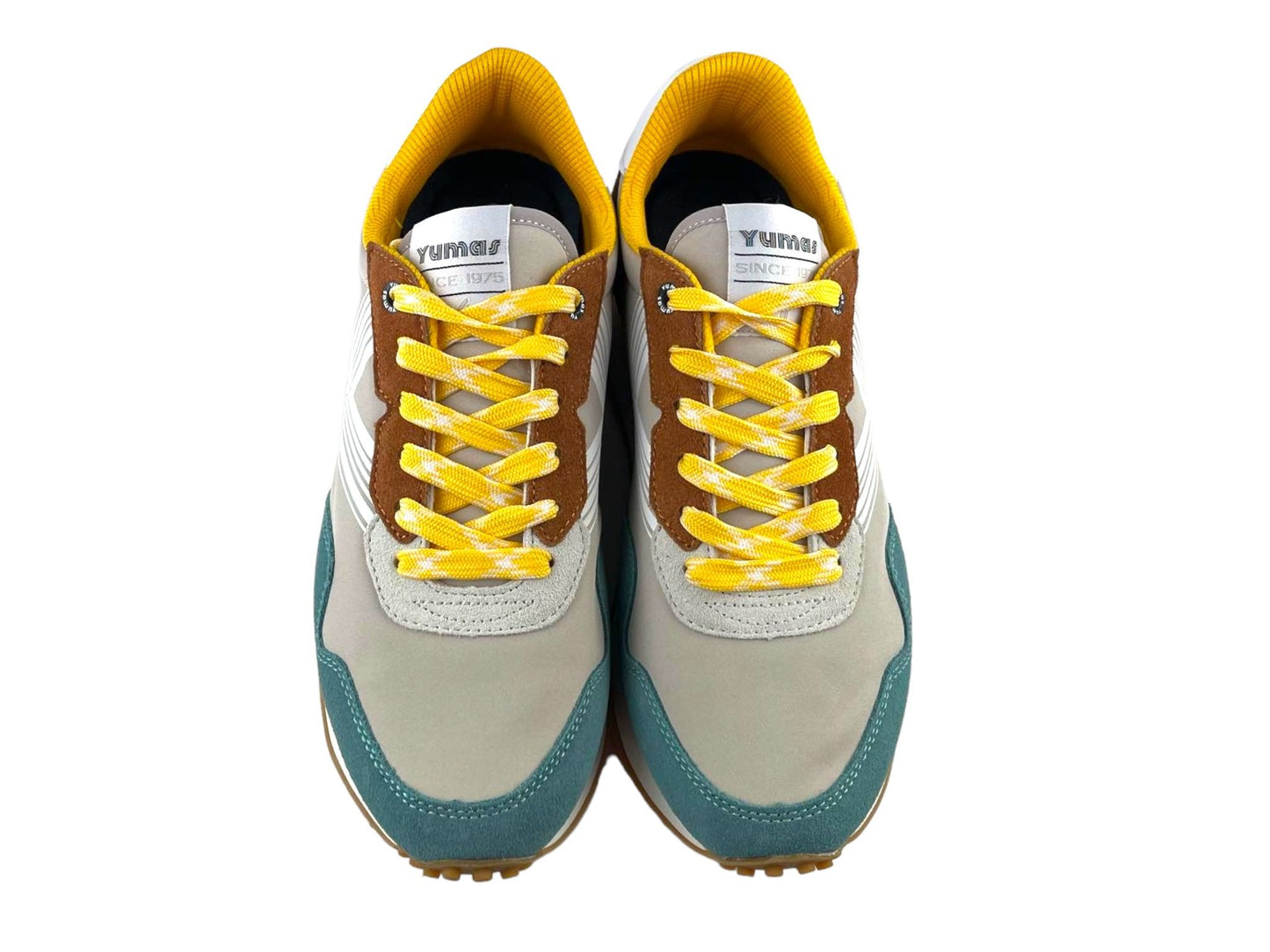 Tenis de hombre en beige con puntera en azul y cordones amarillos con detalles en blanco. Vista por la parte de arriba de unos tenis sobre fondo blanco.