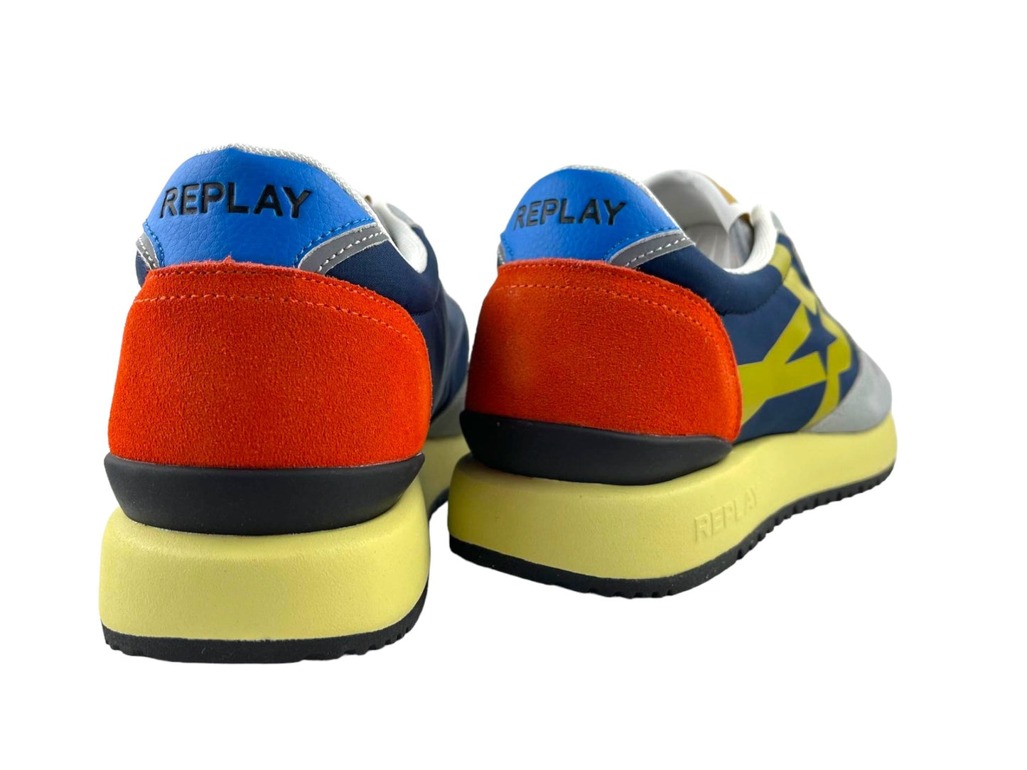 Sneakers de hombre en color azul marino, rojo y suela en amarillo. Vista por la parte trasera sobre fondo blanco.