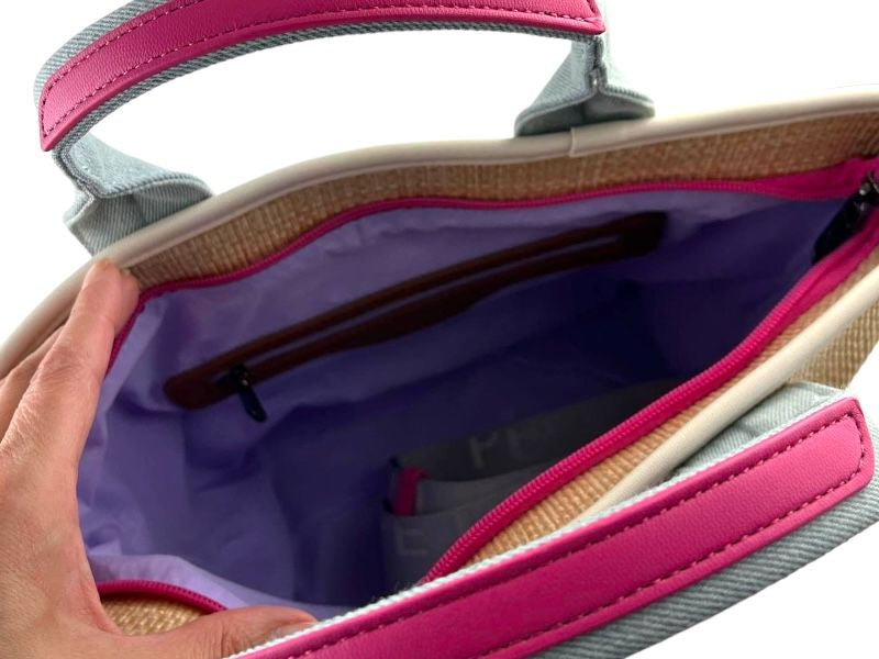 Interior de un bolso con forro lila y detalles en fuxia. Vista interior de un bolso con asas.