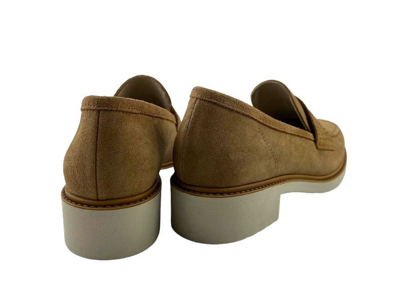 Mocasines de mujer en piel ante beige, con tacón bajo y suela en blanco. Vista por la parte del talión sobre fondo blanco.