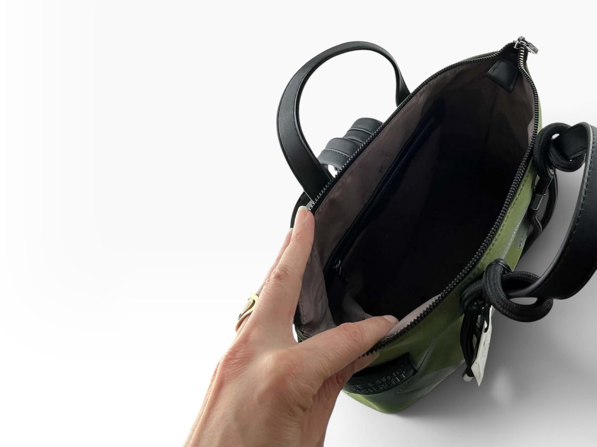 Interior de mochila Pepe Moll verde oliva con forro oscuro, bolsillo interior con cremallera y apertura superior amplia.