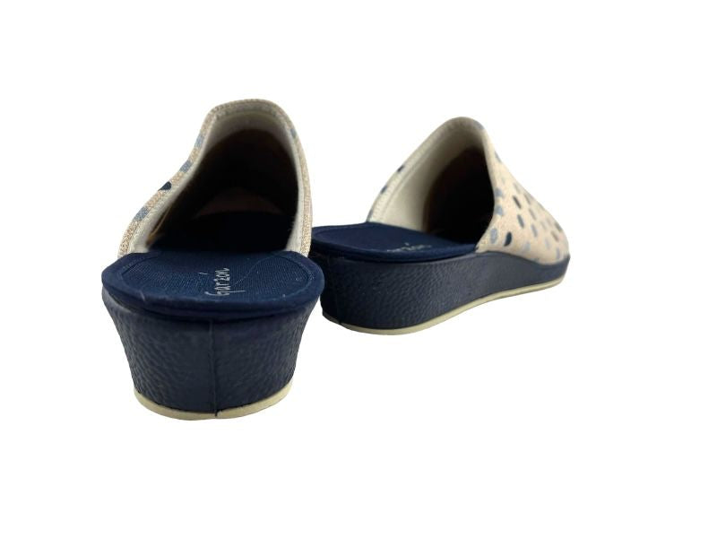Zapatillas de mujer con topos sobre fondo beige, cuña en color marino. Vista por la parte de atrás sobre fondo blanco.