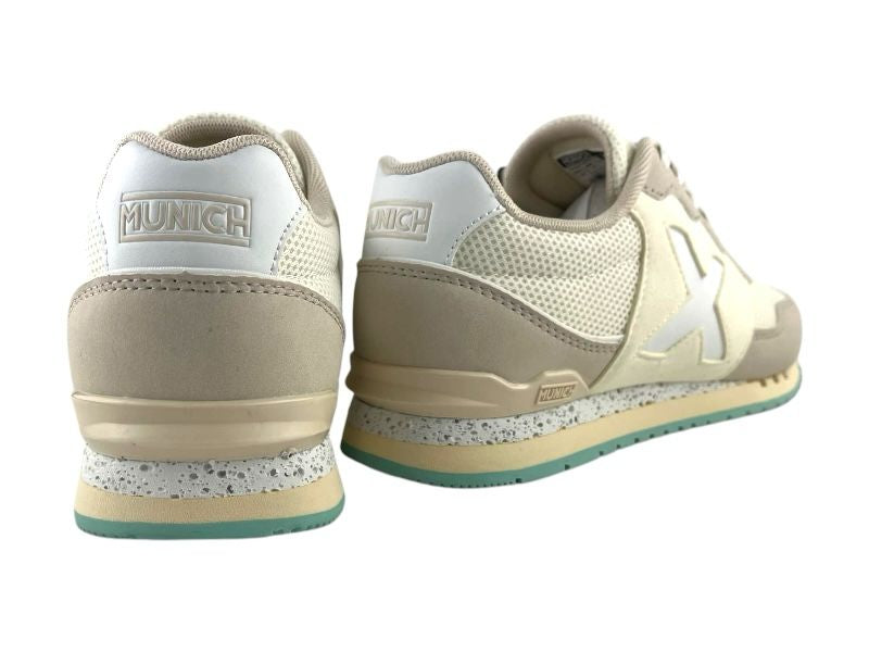 Vista por la parte de atrás de unos sneakers de mujer, estilo retro running, de la marca Munich, en color beige claro, con malla transpirable, talonera con logo de la marca y suela de goma sobre fondo blanco.