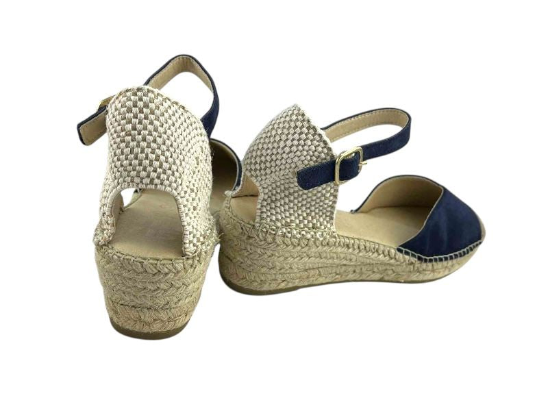 Vista por la parte de atrás de unas alpargatas artesanas azul marino, con cuña baja , con pusera de hebilla en color dorado y talonera en espiga color natural. 