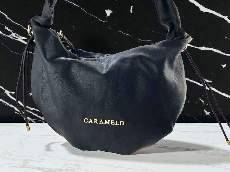 Bolso de mujer de la marca Caramelo en color negro, estilo boho chic, con letras doradas de la marca y asa regulable.