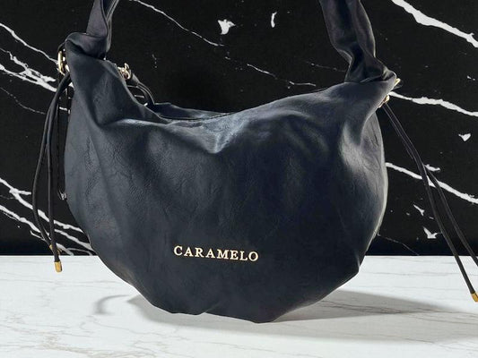 Bolso de mujer de la marca Caramelo en color negro, estilo boho chic, con letras doradas de la marca y asa regulable.