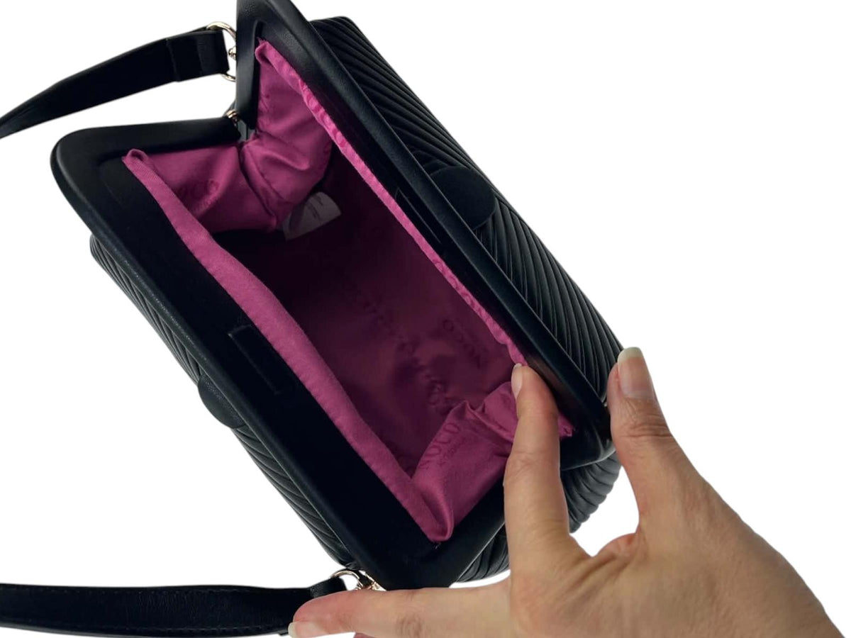 Interior del bolso de mano Noco negro con forro textil fucsia, compartimentos y cierre de imán.