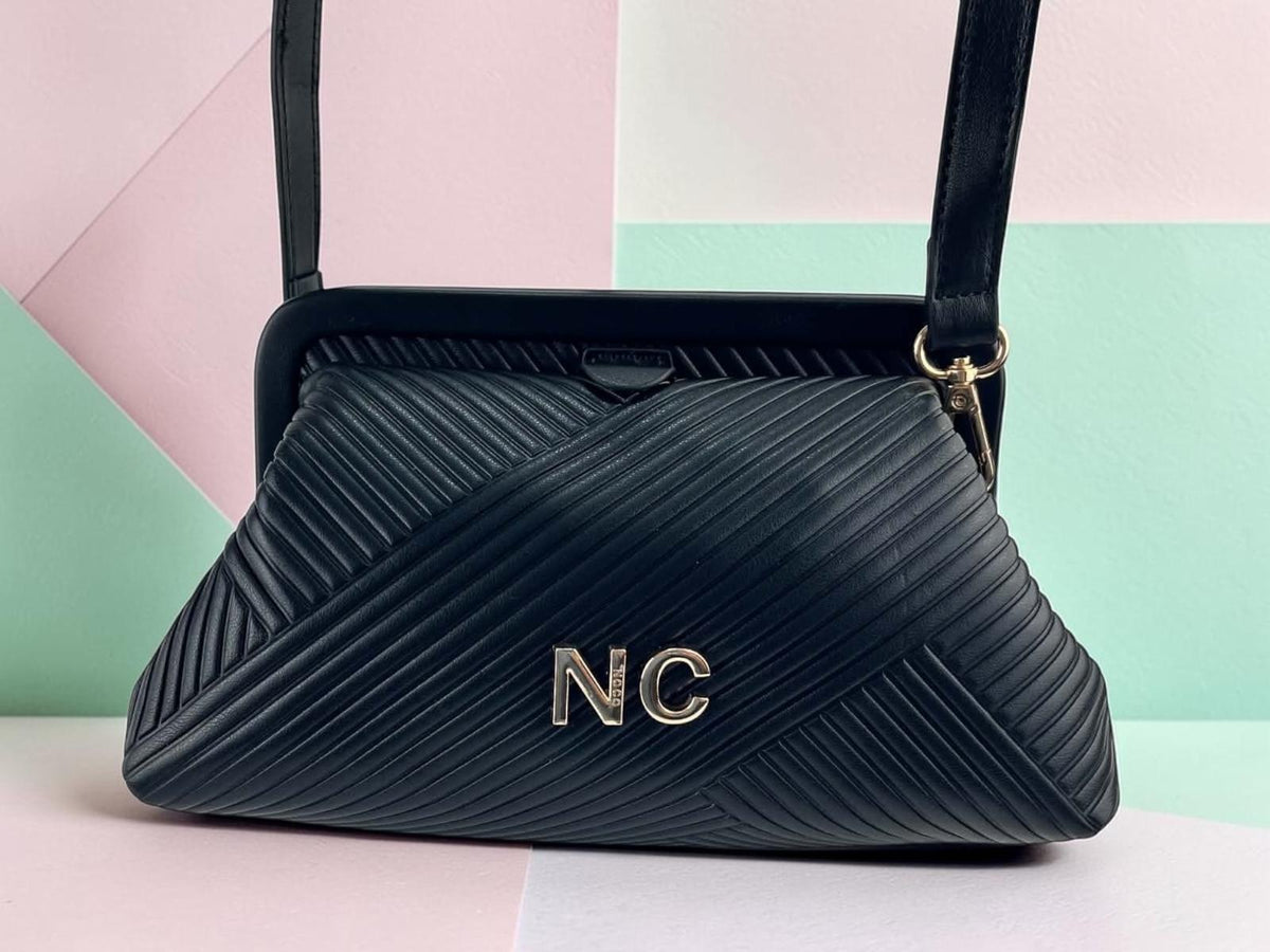 Bolso de mano Noco negro de piel vegana con textura plisada diagonal, detalle NC y correa extraible, vista frontal.