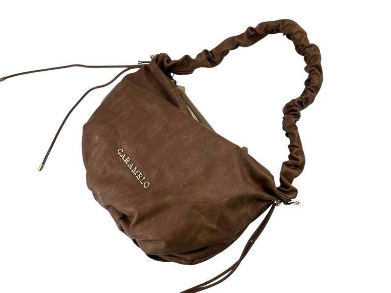 Bolso muy ligero, de la marca española Caramelo, estilo boho chic, con asa regulable en marrón y letras de la marca en dorado.