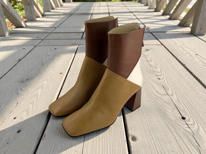 Botines de piel mujer tricolor, camel, marron y blanco,con ountera cuadrada, tacón bloque,cremallera trasera fotografíados sobre una pasarela de madera. 