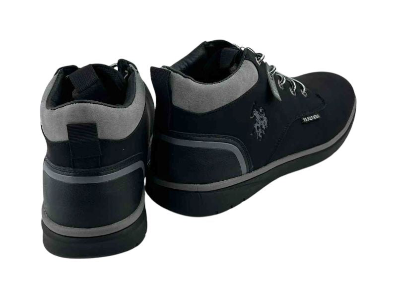 Vista por la parte de atrás de unos botines negros de la marca USPolo en tonos grises, con detalles de la marca en los laterales y lengüeta. Botines cómodos y ligeros con suela bicolor negra y gris.