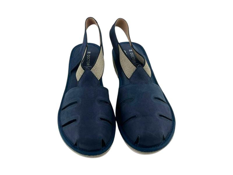 Vista frontal de unas sandalias planas en piel azul, de cortes asimétricos, con elásticos en el empeine y puntera cerrada sobre fondo blanco.