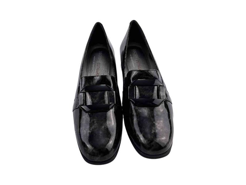 Mocasín de mujer en piel charol negra, con hebillas en el empeine y tacón bajo. Con plantilla extraíble y elásticos para mejor ajuste. 