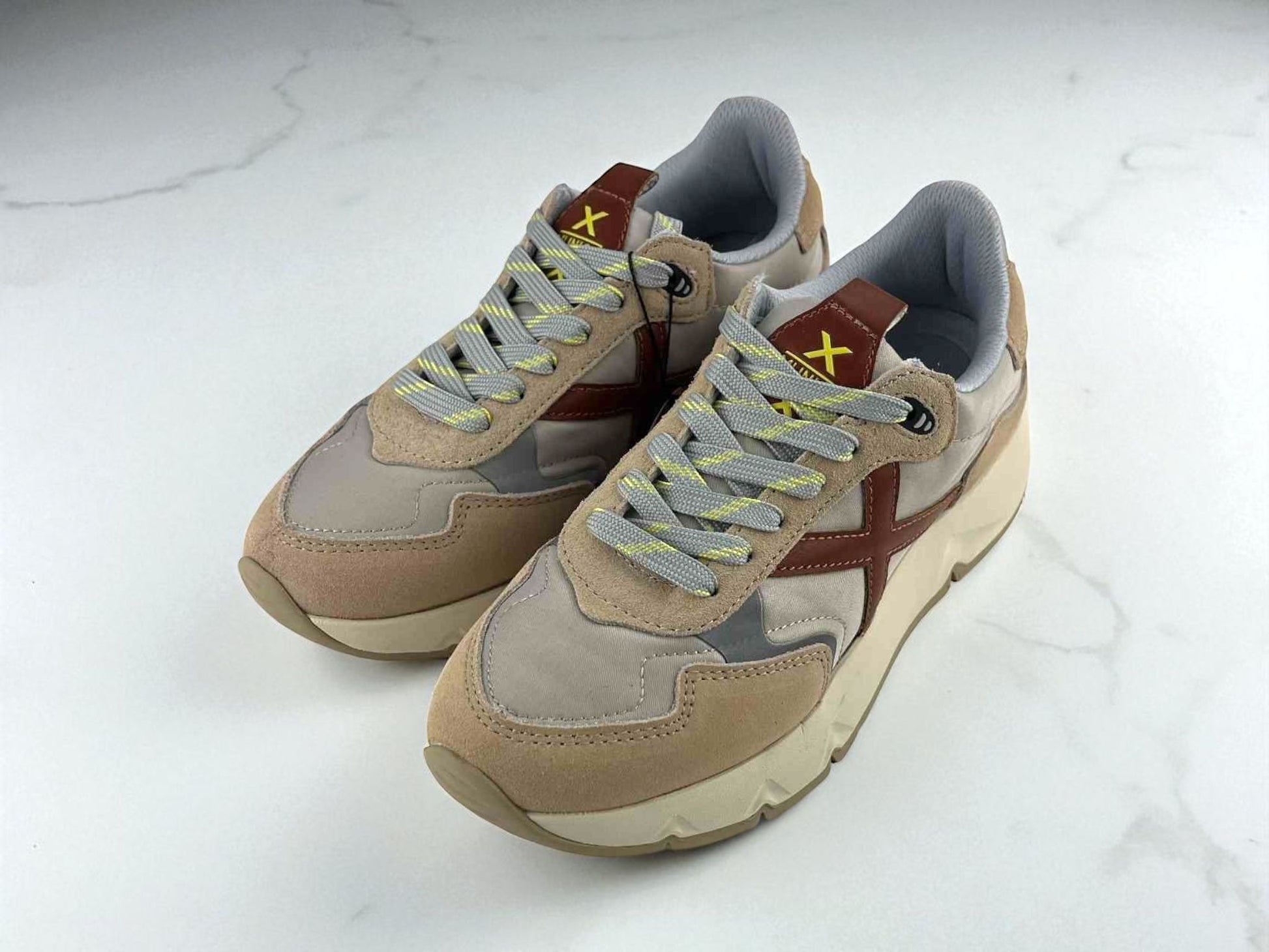 Zapatillas unisex de la marca Munich, estilo urbano retro con detalles en beige y gris y logo en color marrón.