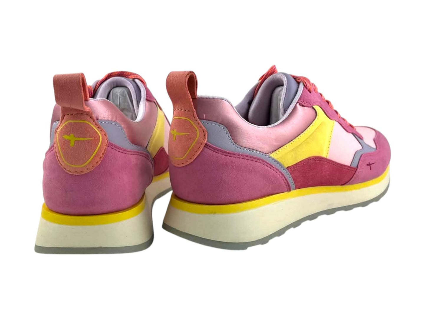 Vista de los talones de las zapatillas Tamaris con tirador rosa y logotipo grabado sobre fondo amarillo.