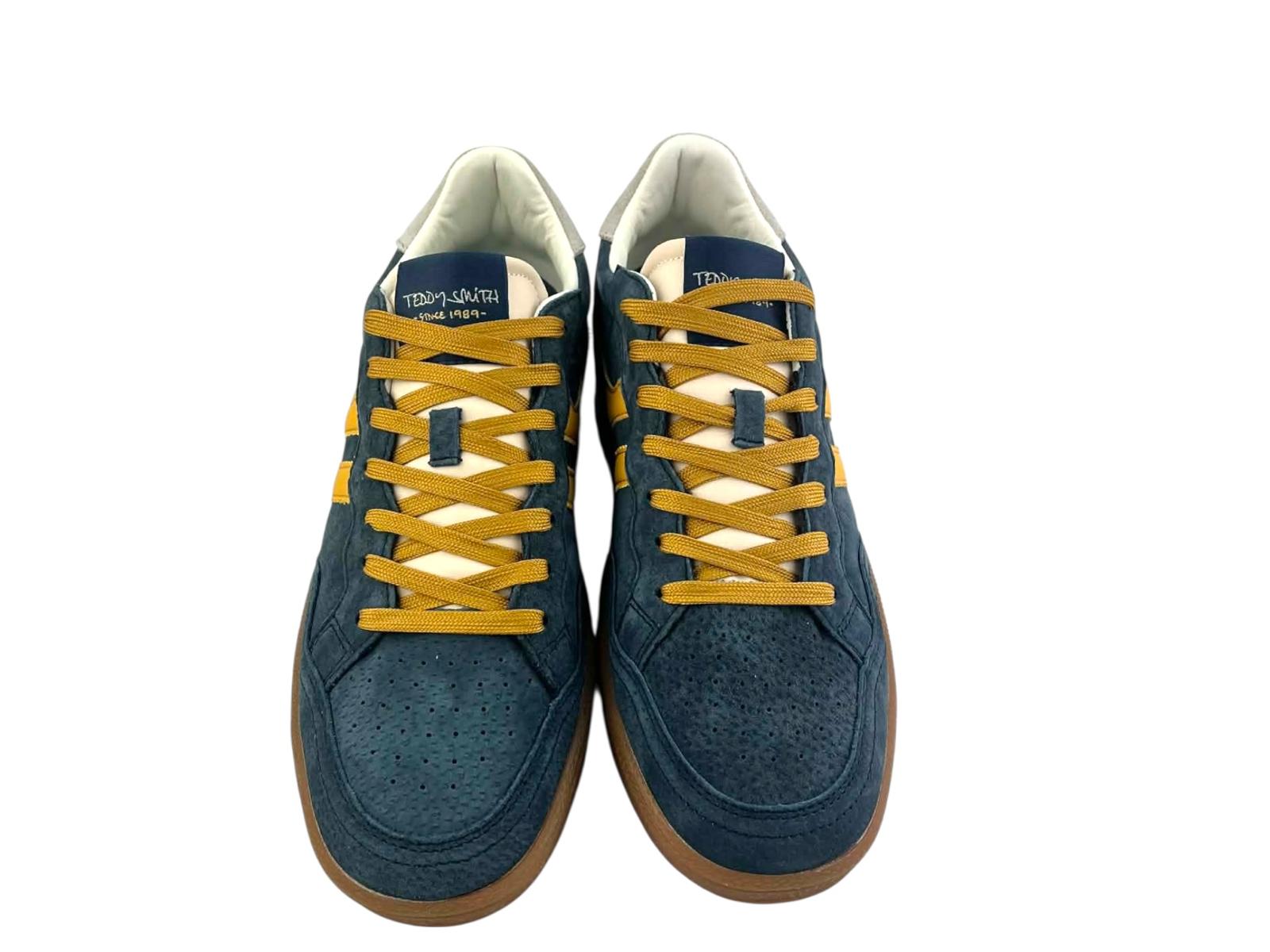 Vista superior centrada de un par de zapatillas retro hombre, mostrando cordones, lengüeta, perforaciones de la puntera y forma general del calzado en azul y amarillo.