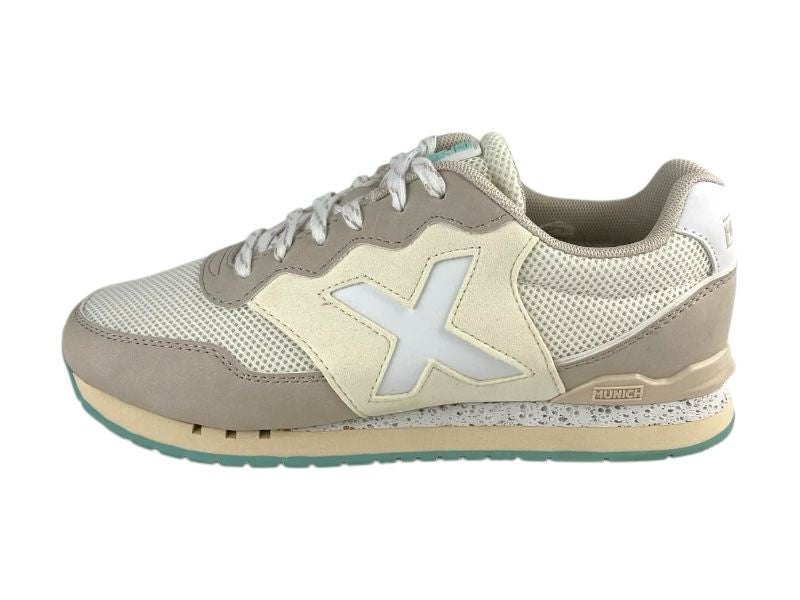 Vista lateral izquierda de unas zapatillas deportivas  Munich, de mujer, en color beige, con logo en el lateral exterior, con cordones y suela de goma bicolor, beige y verde,  sobre fondo blanco.