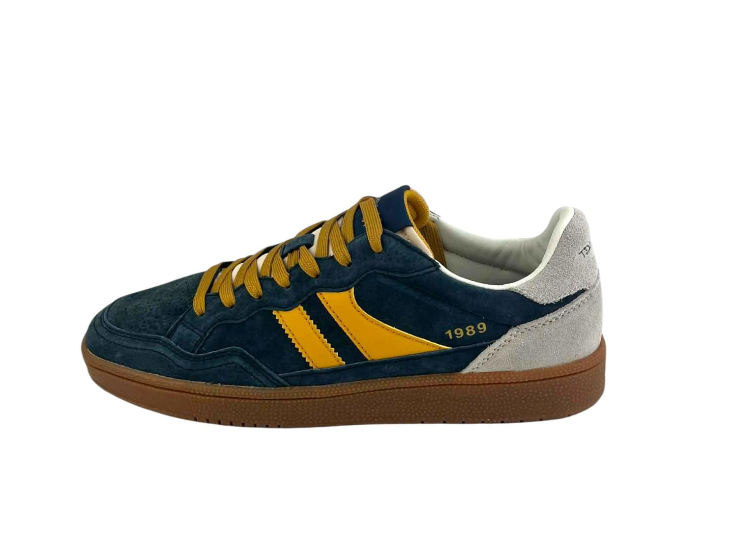 Vista lateral de unas zapatillas retro para hombre, en color azul y amarillo, que destaca la silueta del modelo, el detalle “1989”, los paneles laterales y el perfil de la suela en color caramelo.