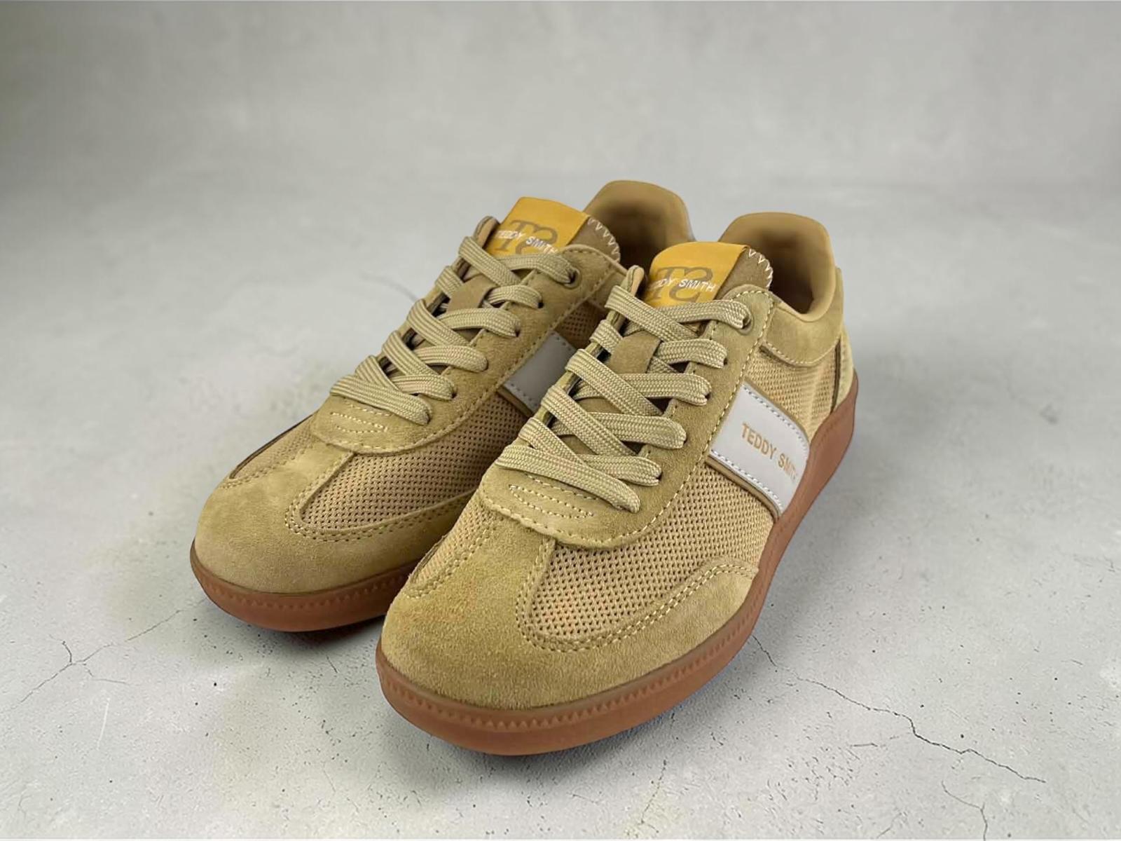 Zapatillas Teddy Smith para mujer de perfil bajo, en color amarillo, paneles de ante serraje y malla perforada transpirable. Cuenta con suela de goma color gum, una raya lateral blanca con texto dorado Teddy Smith, cordones amarillos a juego y logotipo en el talón y lengüeta.