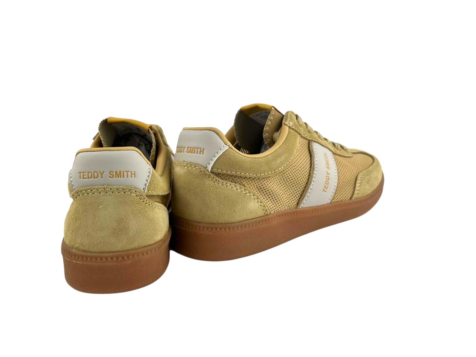 Vista por la parte de atrás de unas zapatillas para mujer de la marca Teddy Smith, en piel ante serraje amarillas, suela de goma y típica franjas laterales blancas de la marca.