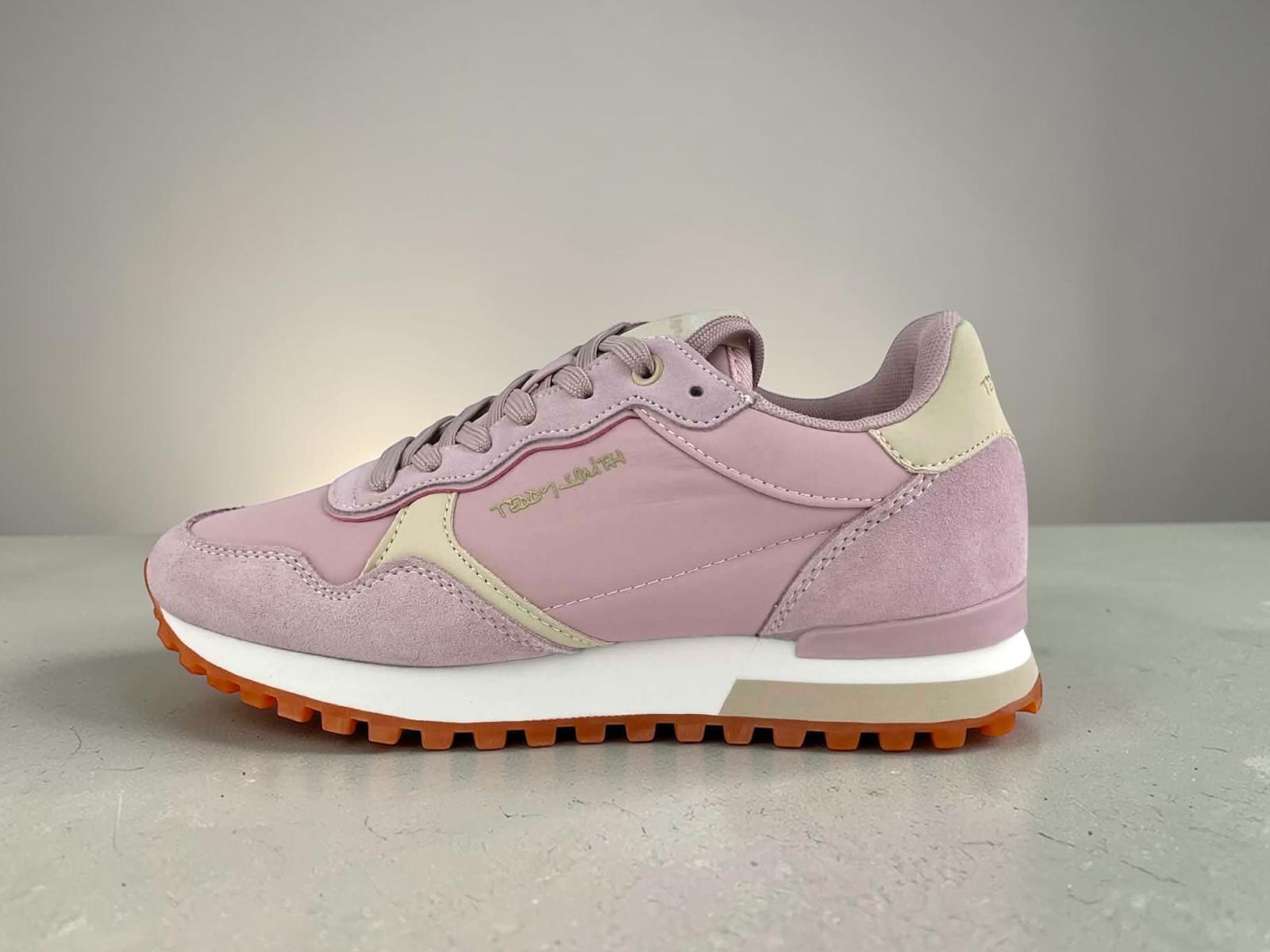 Zapatilla de deporte (sneaker) de perfil para mujer de Teddy Smith. Parte superior en piel serraje rosa empolvado y beige/crema. Suela de goma dentada con patrón waffle color caramelo/naranja. Logotipo dorado visible en el lateral y la lengüeta. Cordones rosas. Fondo gris.